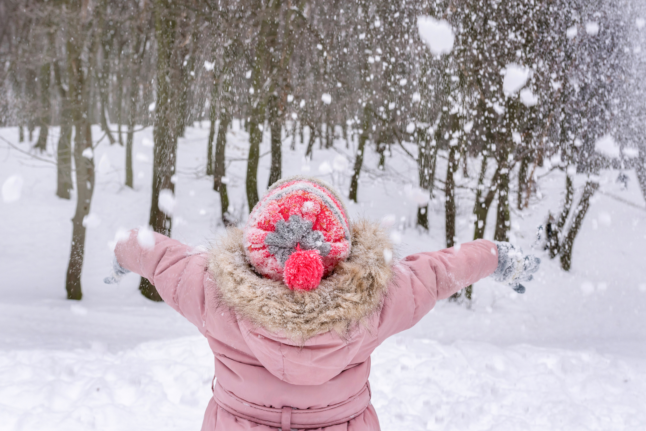 young-girl-in-pink-winter-hat-and-coat-arms-out-to-embrace-the-wintr-weather