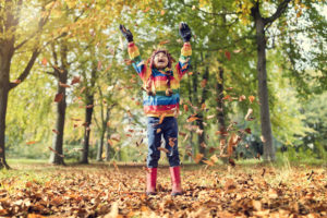 child-throwing-leaves-in-the-air-in-celebration-of-fall